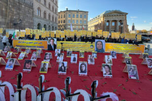 Mynttorget, Stockholm, 12 oktober 2024: Svensk- och exiliranier, sympatisörer till Iranska nationella motståndsrådet (NCRI), håller upp plakat under en demonstration som uppmanar Sverige att terrorstämpla revolutionsgardet och uttrycker solidaritet med politiska fångar i Iran som deltar i kampanjen ”Tisdagar mot avrättningar”.